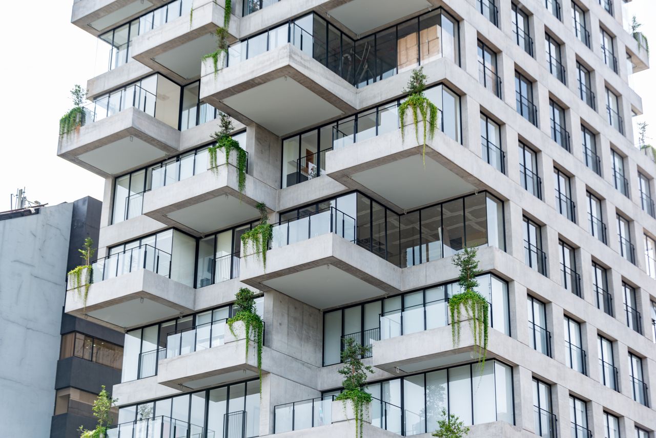 Contemporary residential building featuring geometric design and lush balconies with green plants.